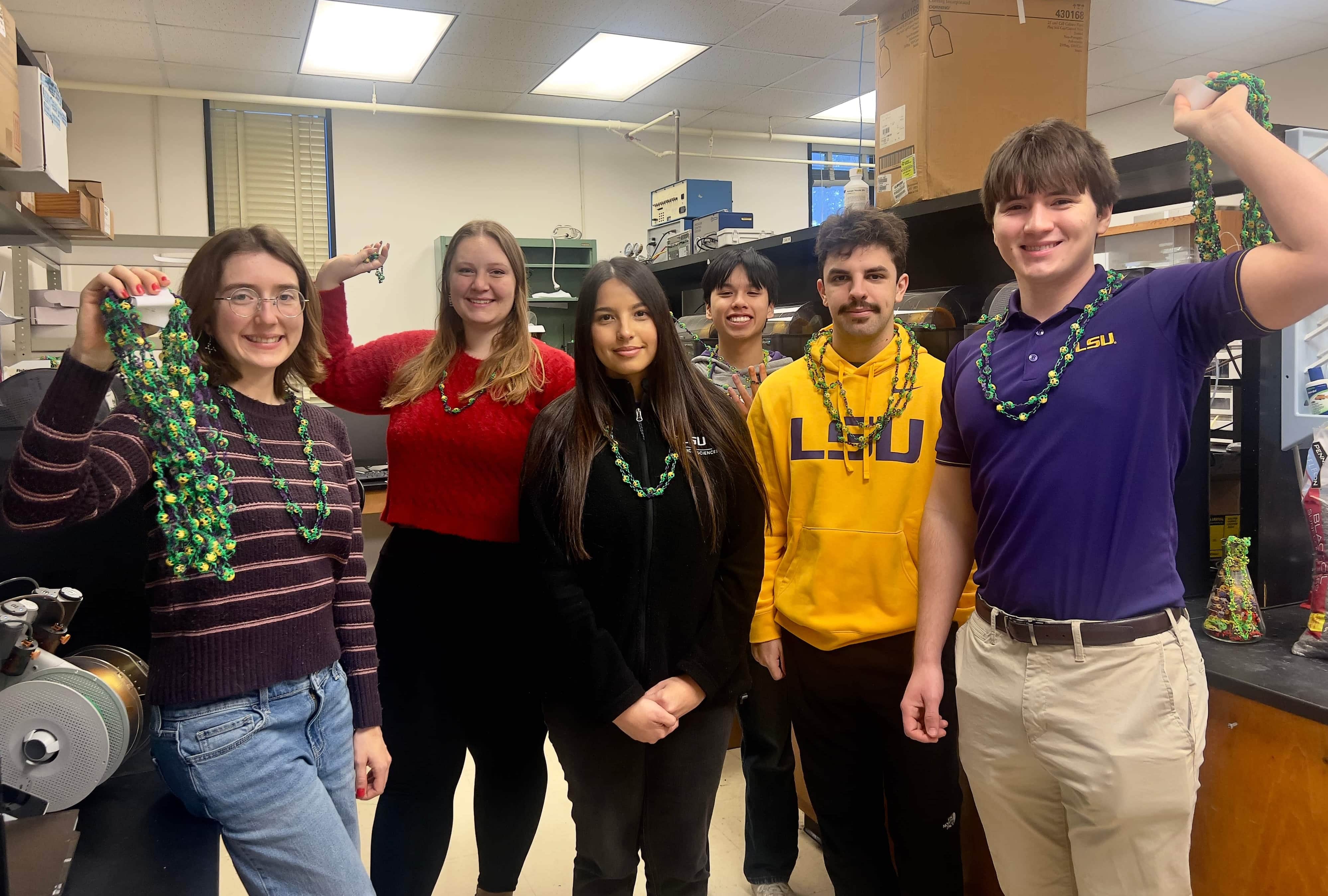 students holding mardi gars beads in lab
